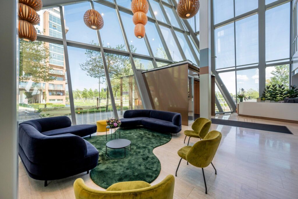 Moderne ontvangsthal aan de David Ricardostraat met grote glazen ramen, kleurrijk meubilair en een stijlvolle zithoek.